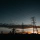 Lattice transmission towers and power lines silhouetted at sunset