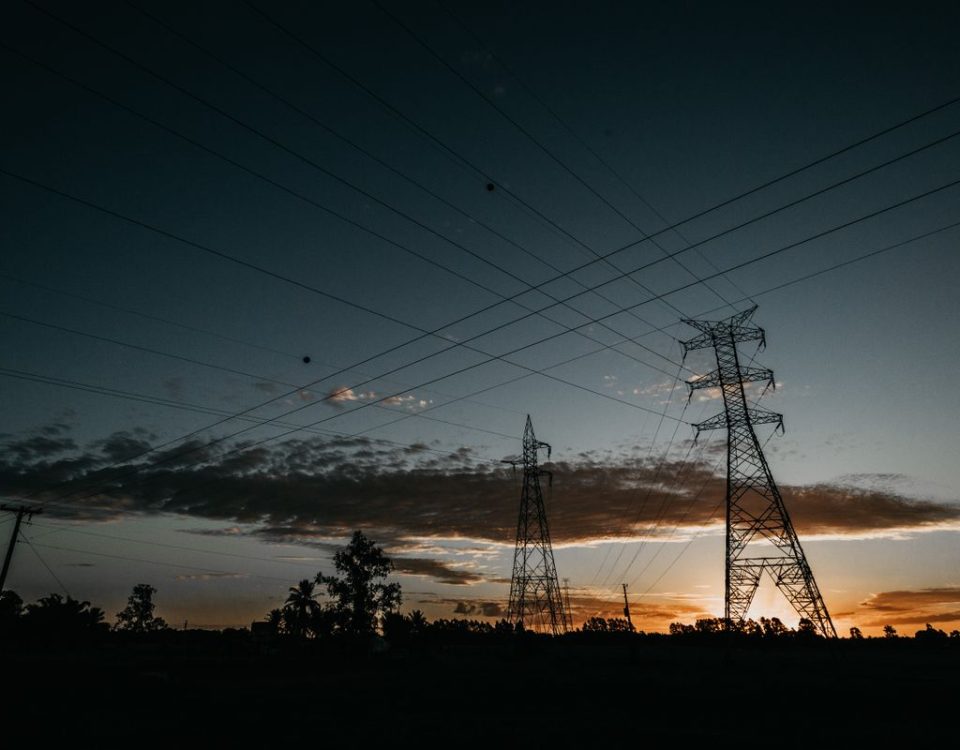 Lattice transmission towers and power lines silhouetted at sunset